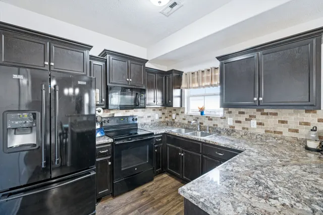 a kitchen with stainless steel appliances granite countertop a sink stove and refrigerator