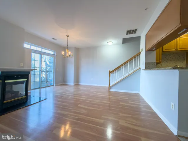 a view of an empty room with wooden floor fireplace and a window