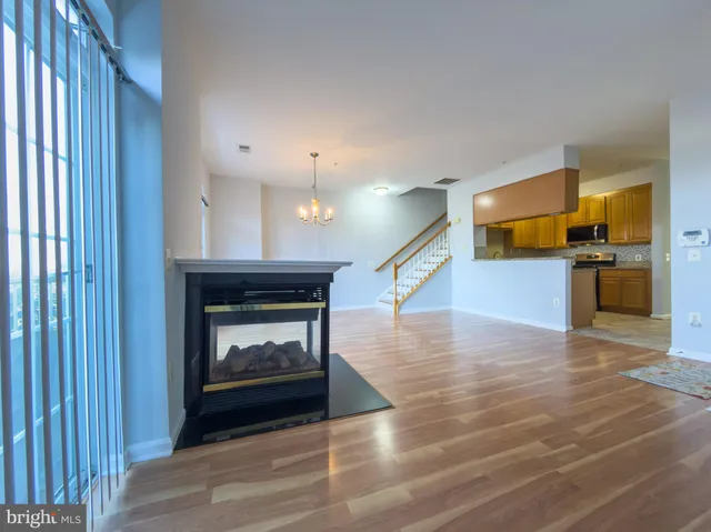a view of an empty room with wooden floor fireplace and a window
