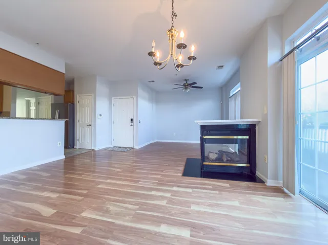 a view of a livingroom with a fireplace a chandelier and wooden floor