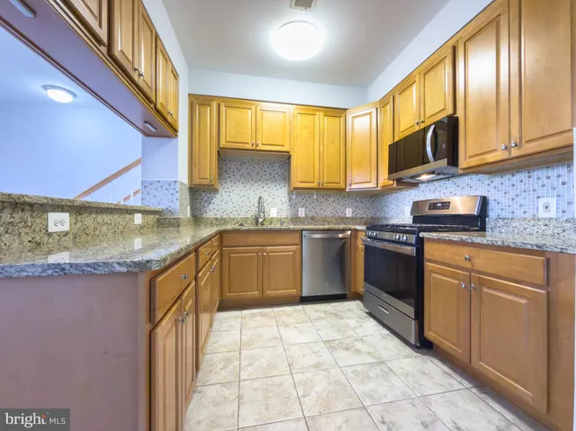 a kitchen with stainless steel appliances granite countertop a stove sink microwave and cabinets