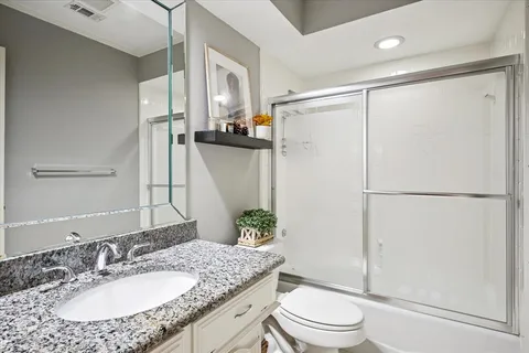 a bathroom with a granite countertop sink toilet and shower