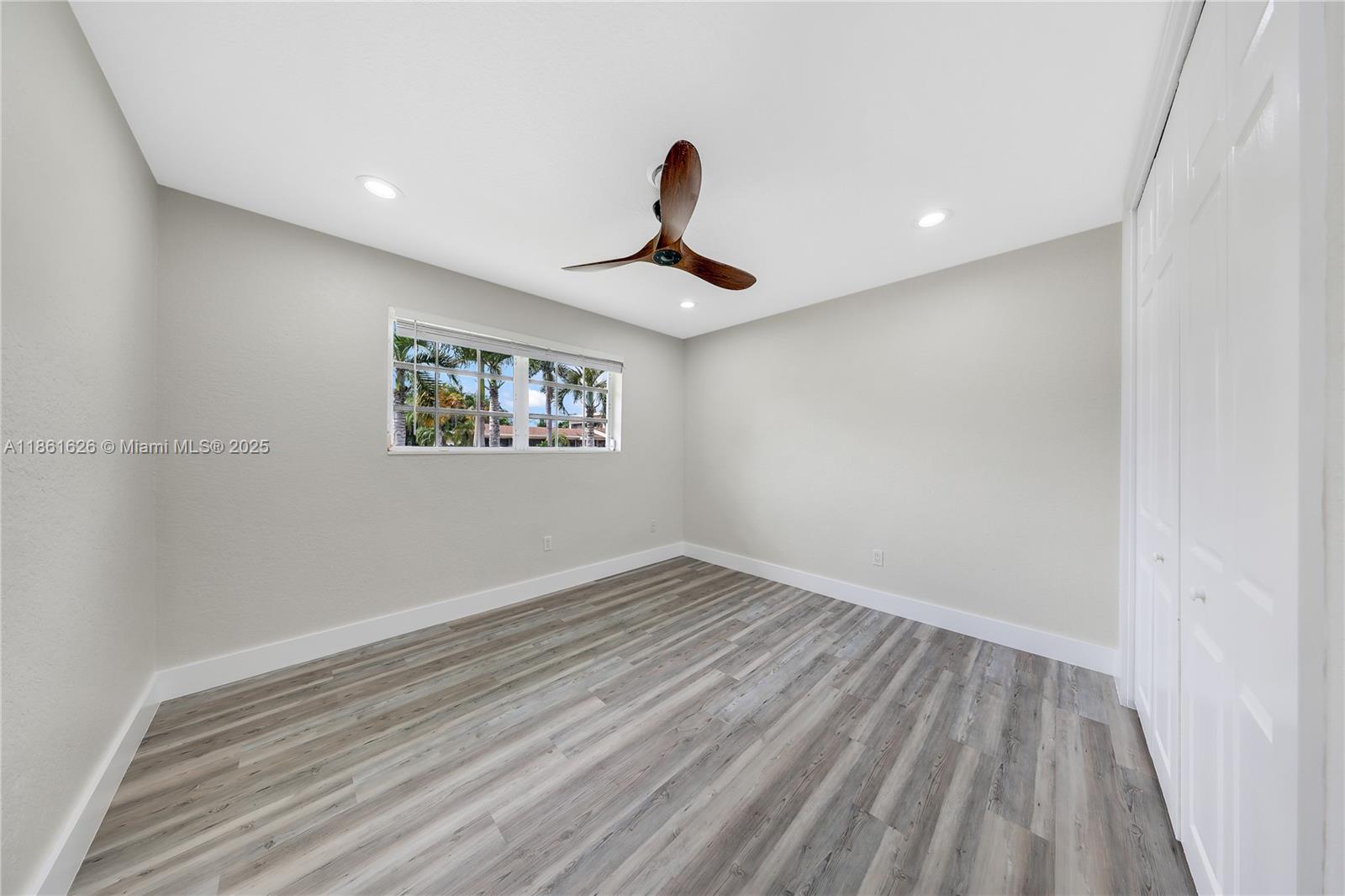 8355 Southwest 89th Street Miami, FL 33156 - Photo 16 of 29 a view of a room with wooden floor ceiling fan and window