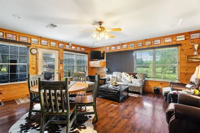 a dining room with furniture large windows and wooden floor