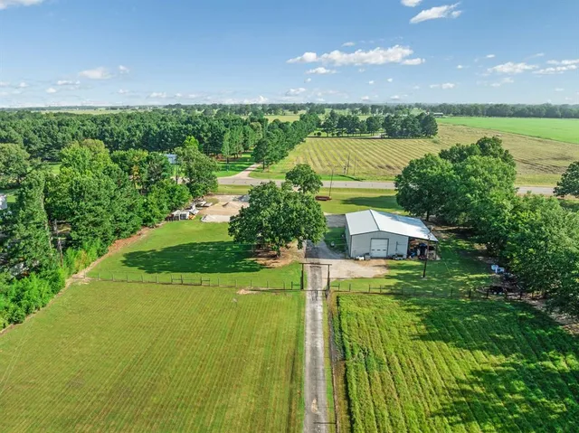 an aerial view of a residential houses with outdoor space and trees