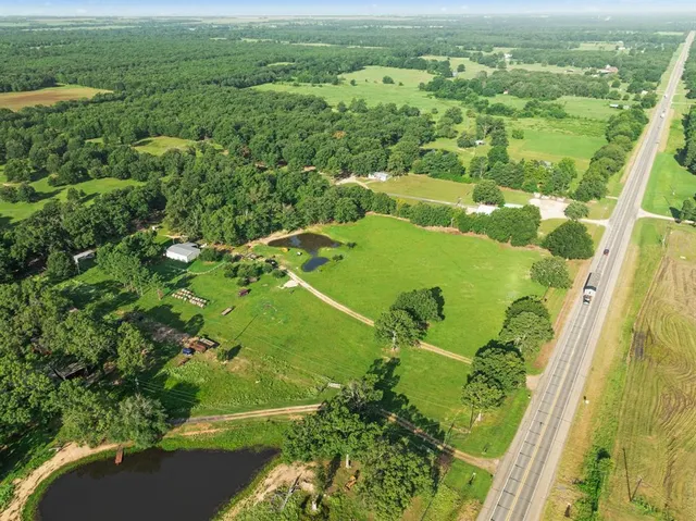 an aerial view of a residential houses with outdoor space and trees
