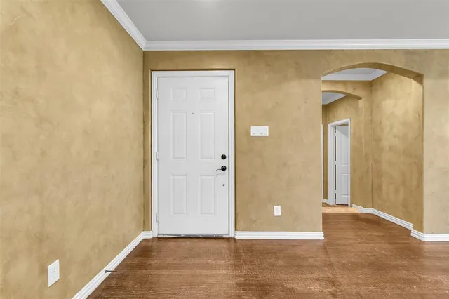 a view of an empty room with kitchen and a window