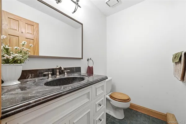 a bathroom with a granite countertop sink a toilet and a mirror