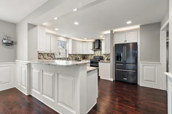 a kitchen with a refrigerator stainless steel appliances wooden floor and a window