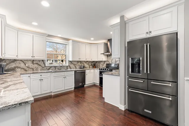 a kitchen with granite countertop white cabinets and stainless steel appliances