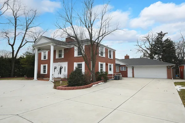 a front view of a house with garden and trees