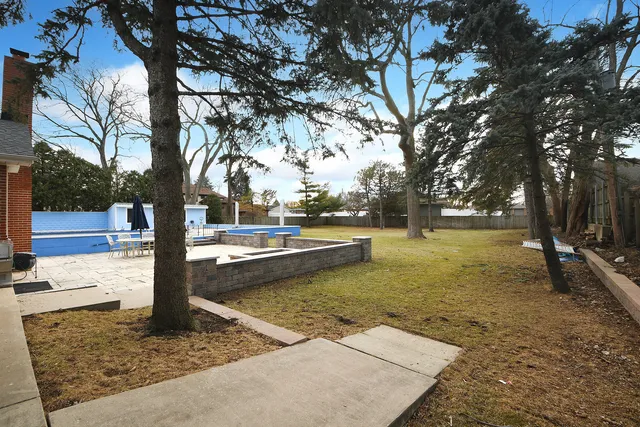 an aerial view of a house with swimming pool and large trees