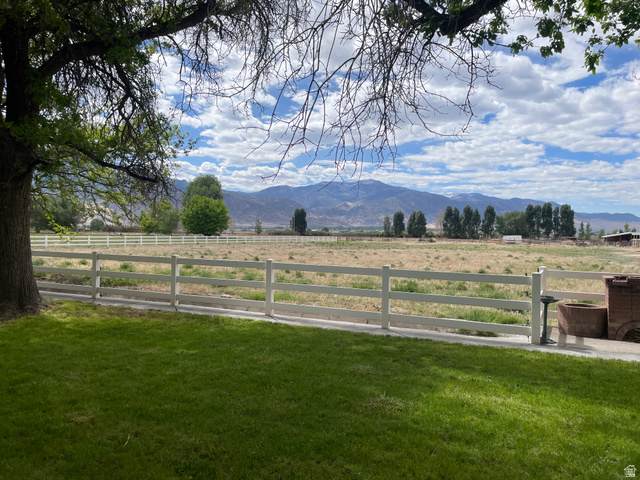 438 East Main Street Elsinore, UT 84724 - Photo 10 of 43 Expansive outdoor space featuring a manicured lawn, white perimeter fencing, and distant mountain scenery under a cloudy sky
