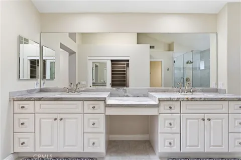 a bathroom with a granite countertop double vanity sink and mirror