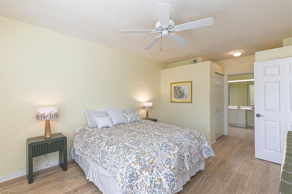 6804 Satinleaf Road South, Unit 102 Naples, FL 34109 - Photo 15 of 35 a bedroom with a bed and a chandelier