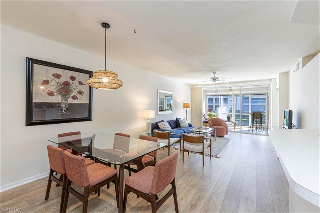 6804 Satinleaf Road South, Unit 102 Naples, FL 34109 - Photo 35 of 35 a dining room with furniture wooden floor a chandelier and a painting