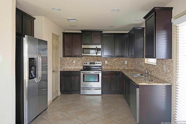 a kitchen with stainless steel appliances granite countertop a refrigerator and a stove