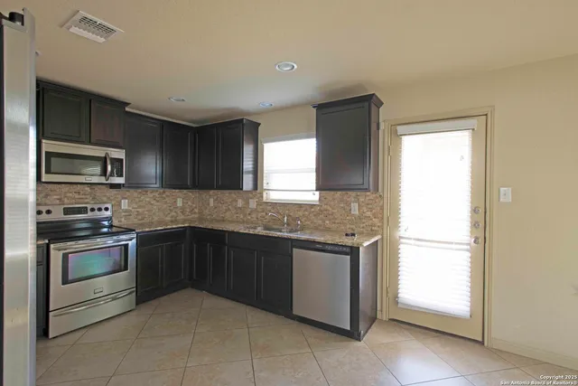 a kitchen with stainless steel appliances granite countertop cabinets and window