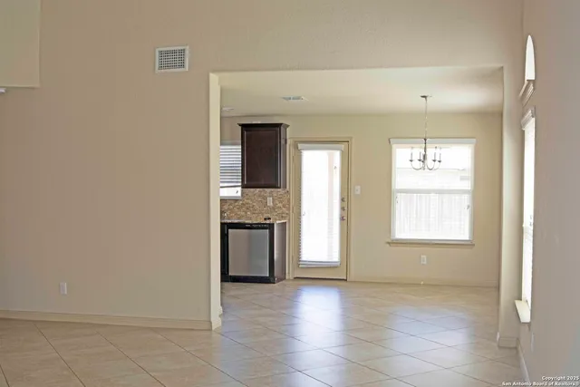 a view of an empty room with a kitchen and a window