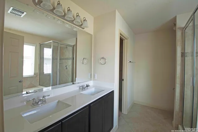 a bathroom with a double vanity sink a mirror and a shower