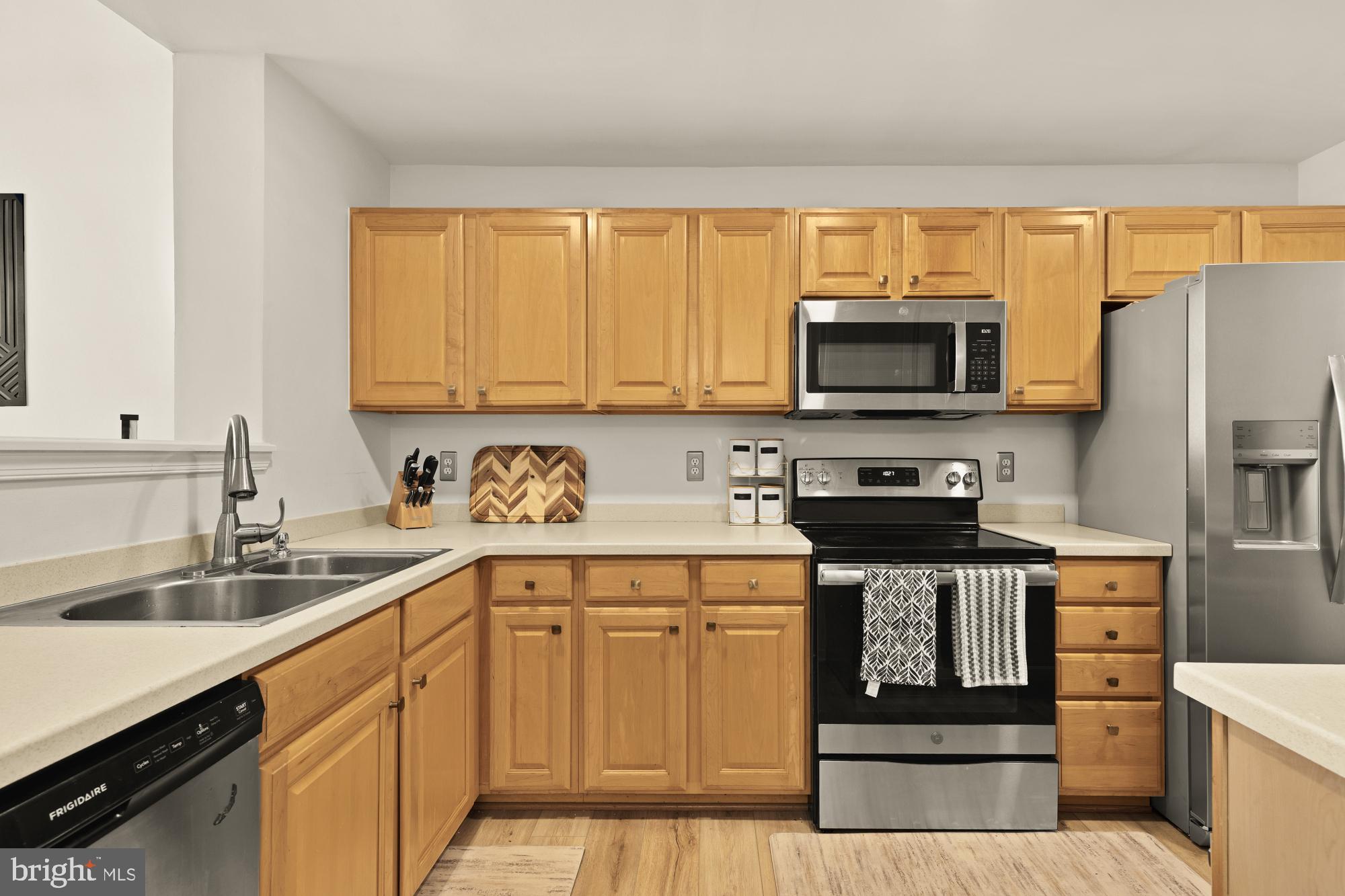 1887 Crescent Park Drive, Unit 111A Reston, VA 20190 - Photo 10 of 27 a kitchen with stainless steel appliances granite countertop a stove top oven a sink dishwasher and a refrigerator with wooden cabinets