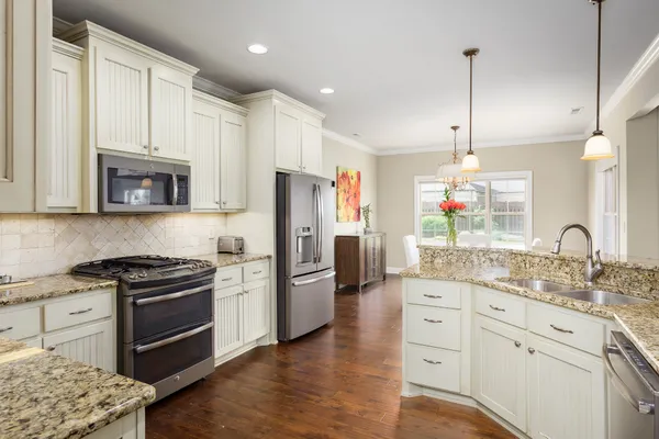 a kitchen with stainless steel appliances granite countertop a refrigerator a stove a sink dishwasher and a refrigerator with wooden floor