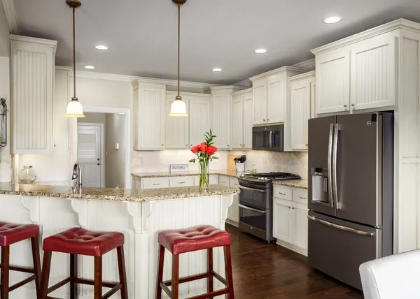 a kitchen with stainless steel appliances kitchen island granite countertop a refrigerator a stove a sink and chairs with wooden floor