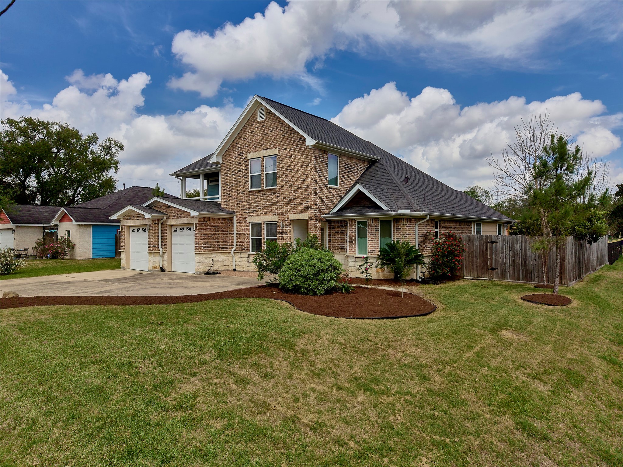 4219 Redbud Street Houston, TX 77051 - Photo 1 of 25 This photo showcases a charming two-story brick house with a well-maintained lawn and a fenced backyard. It features a two-car garage and a spacious driveway, situated in a quiet neighborhood.