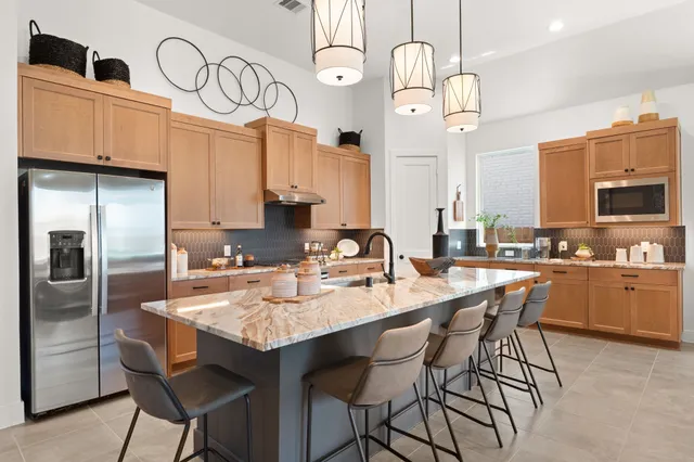 a kitchen with cabinets a sink stainless steel appliances and chairs