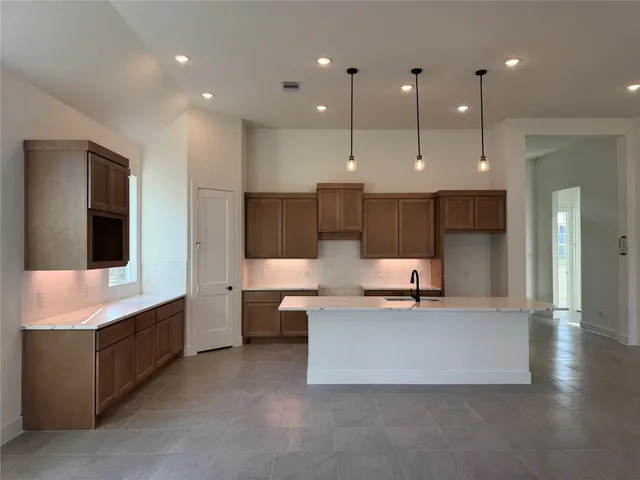 a large kitchen with stainless steel appliances kitchen island a large counter top a sink appliances and cabinets