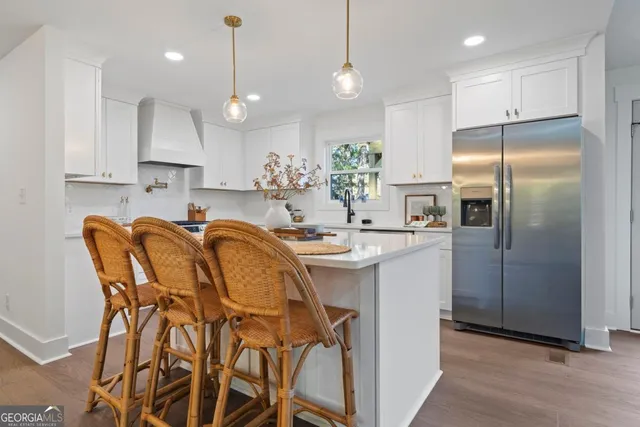 a kitchen with granite countertop a table chairs refrigerator and microwave