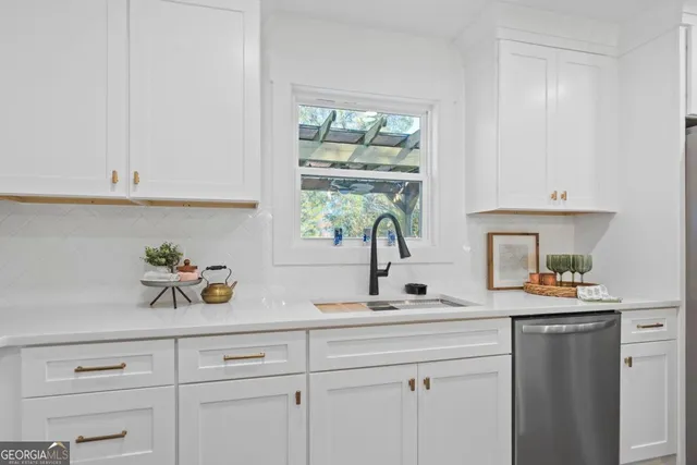 a kitchen with white cabinets and a window