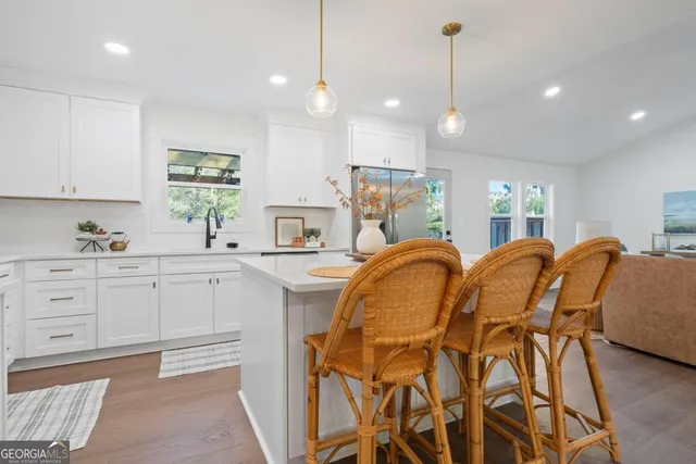 a very nice looking kitchen with granite countertop a stove a sink a window and dining table