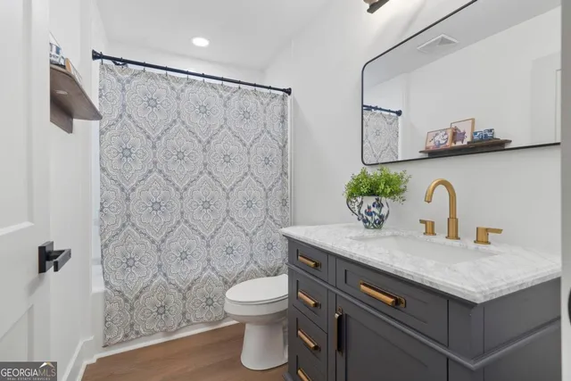 a bathroom with a granite countertop sink a toilet and a shower curtain
