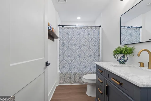 a bathroom with a granite countertop sink a toilet and shower