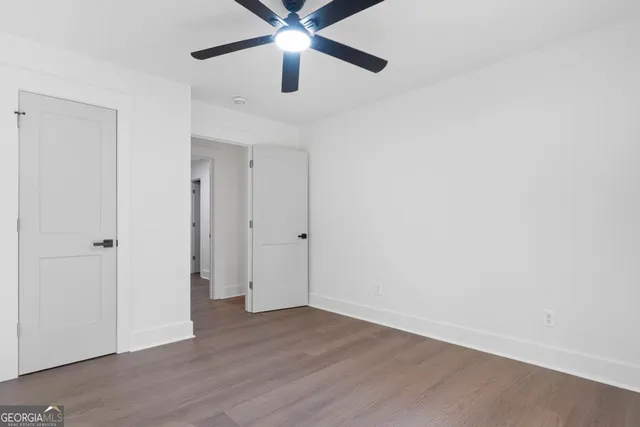 an empty room with wooden floor and ceiling fan