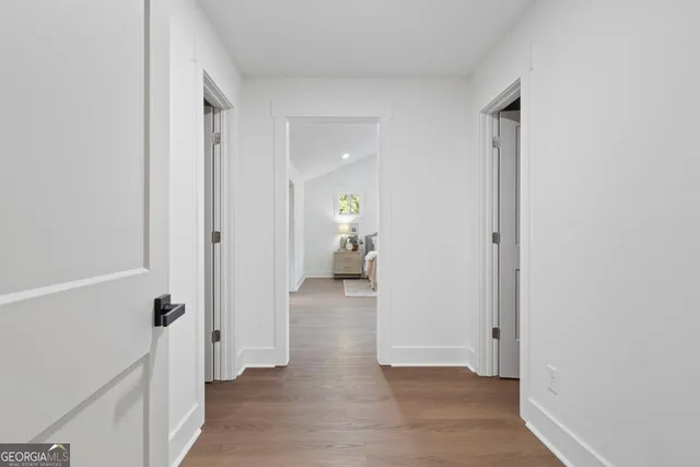 a view of a hallway with wooden floor and a bathroom
