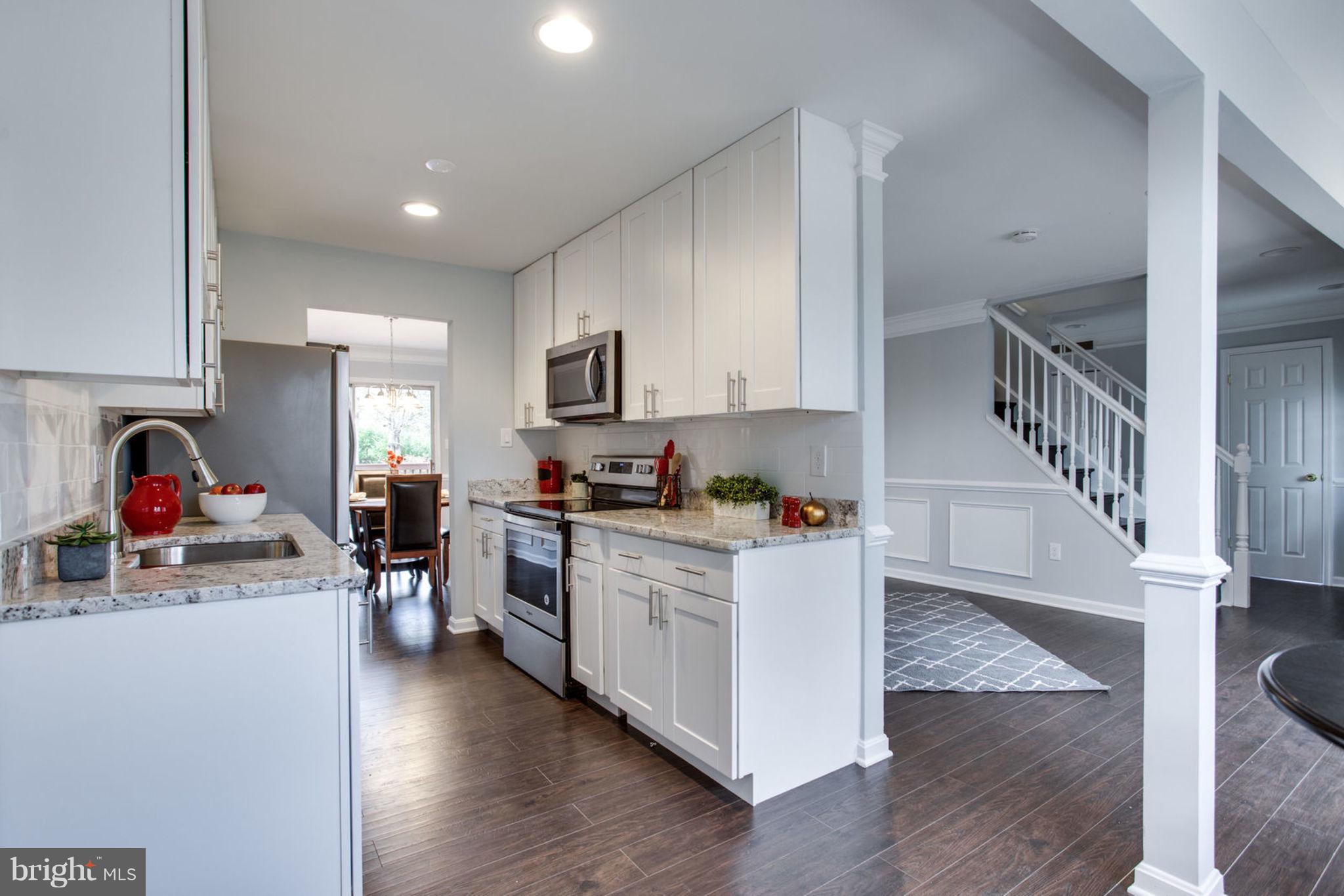 14312 Sturtevant Road Silver Spring, MD 20905 - Photo 16 of 43 a kitchen with stainless steel appliances lots of white cabinets a sink dishwasher and a stove with wooden floor