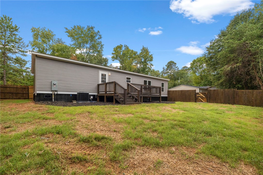 474 Bryant Road Pelzer, SC 29669 - Photo 42 of 44 An expansive grassy backyard features a spacious wooden deck and a secure perimeter fence.