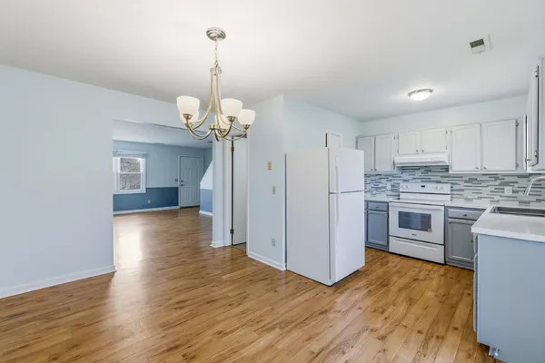 a kitchen that has a lot of white cabinets a sink and stainless steel appliances