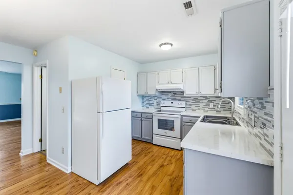 a kitchen with a sink cabinets stainless steel appliances and wooden floor