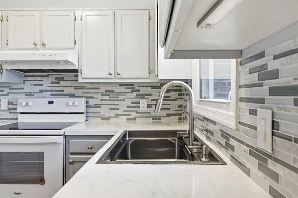 a kitchen with granite countertop a sink a stove and cabinets
