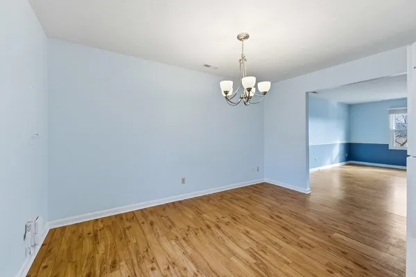 a view of empty room with wooden floor and chandelier