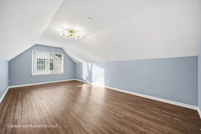 an empty room with wooden floor chandelier fan and windows