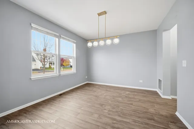 a view of an empty room with window and wooden floor