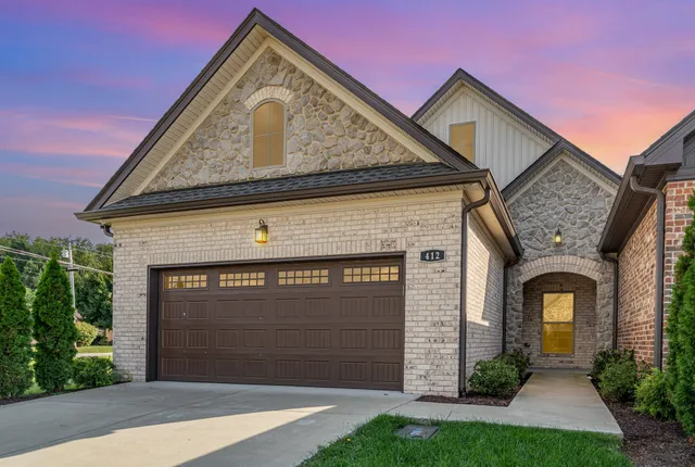 a front view of a house with a garden and garage