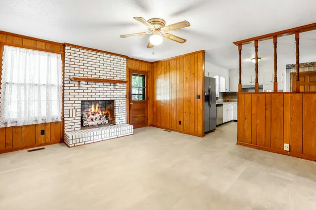 an empty room with windows a fireplace and a chandelier fan