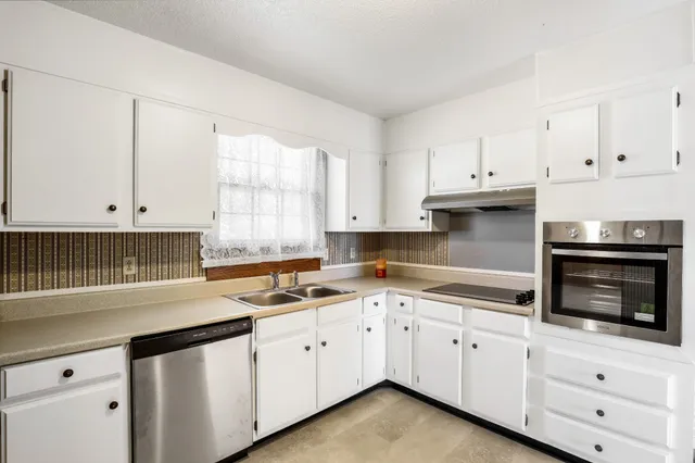 a kitchen with granite countertop white cabinets white appliances and a sink