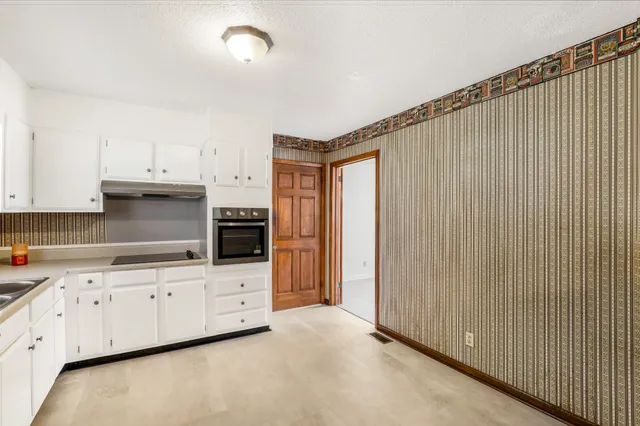a kitchen with granite countertop white cabinets and white appliances