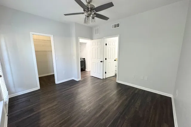 an empty room with wooden floor fan and windows